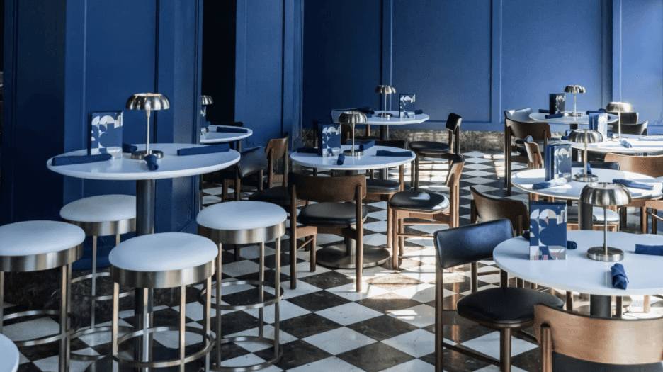 A restaurant interior featuring blue walls and white tables, creating a bright and inviting atmosphere for diners.